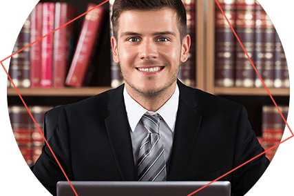 Estudante de direito branco sorrindo usando um notebook e com uma estante de livros ao fundo